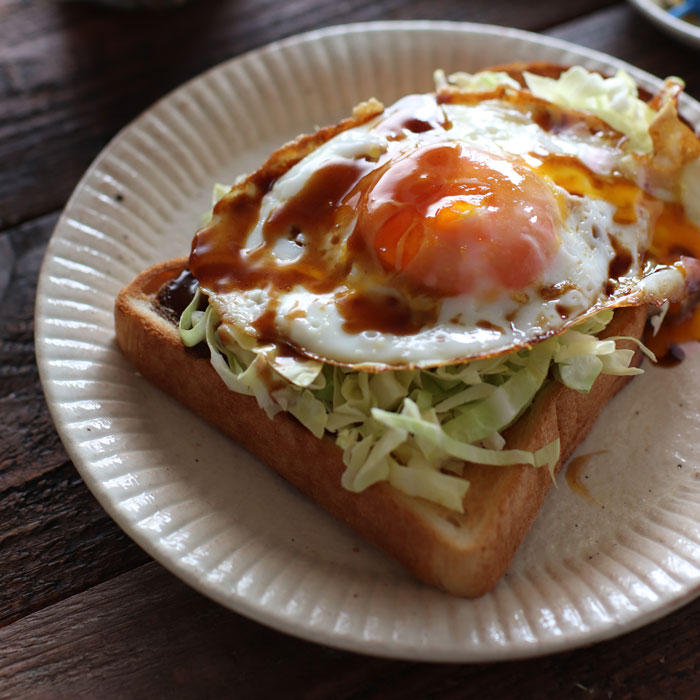 千切りキャベツに半熟目玉焼きをオン、味付けはソースで。