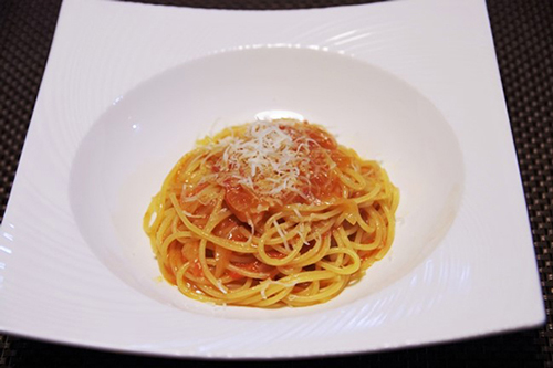 フルーツトマトのスパゲッティ。バターで炒めたにんにくと新玉ねぎを蒸し焼きにし、フルーツトマトを加え、さら蒸し焼きに。塩、こしょう、オリーブオイルで味付け。パルミジャーノチーズをすり下ろしています。